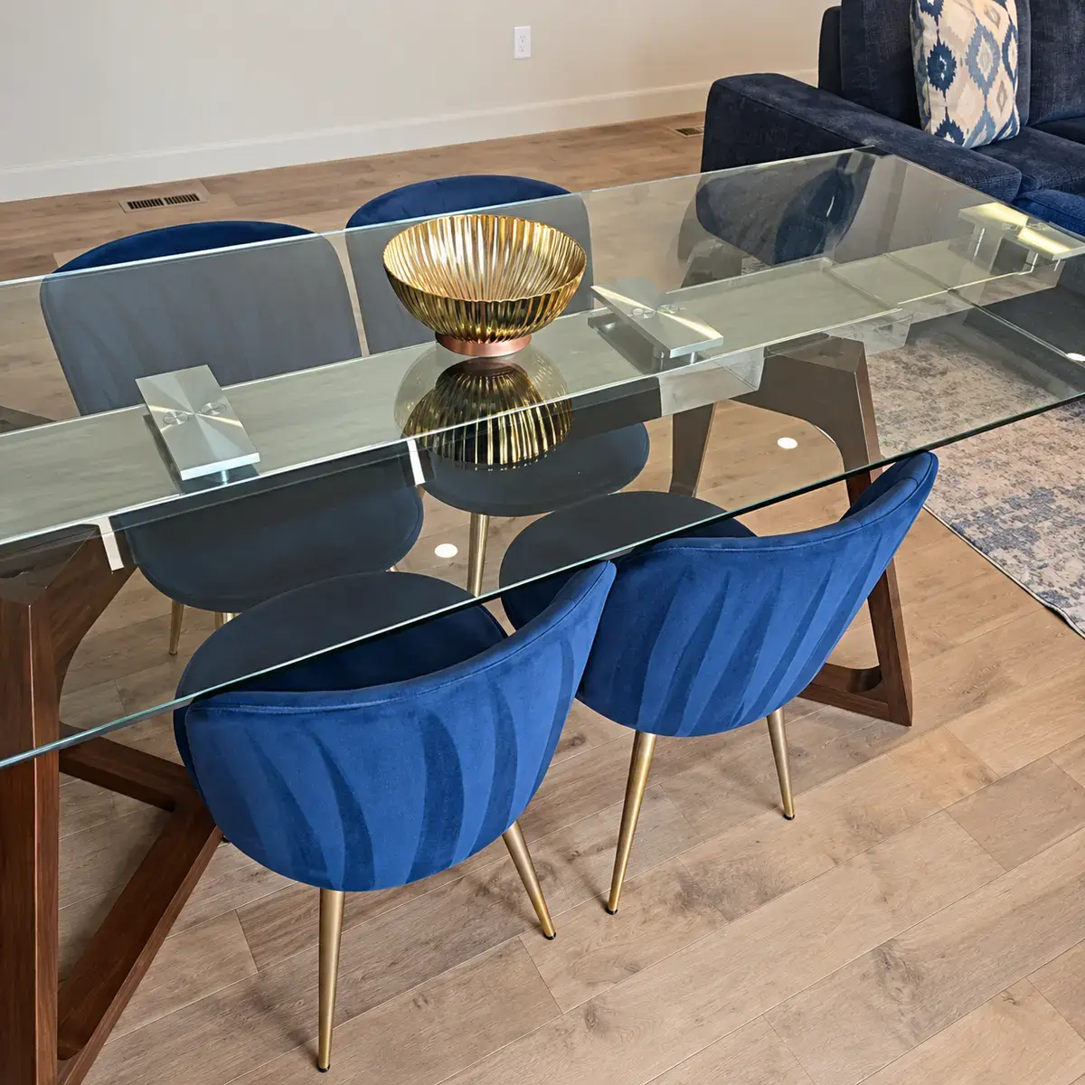 Clean glass dining table and blue chairs prepared for arriving guests.